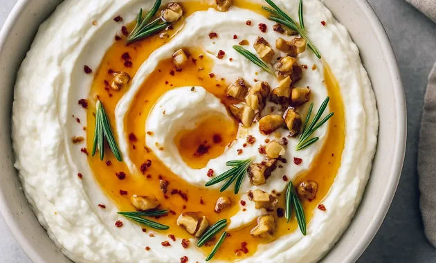 Bowl of whipped ricotta topped with hot honey drizzle, chopped walnuts, and rosemary, surrounded by toasted bread slices – perfect Pre Dinner Snack Ideas and easy Snacks To Bring To A Gathering for Girls Day Food, Fun Appetizers To Make, and casual Hosting Appetizers Entertaining or Meals For Party. Great as Hors D’oeuvres Ideas Easy, trendy East Coast Appetizers, or delicious Tapas Appetizers.