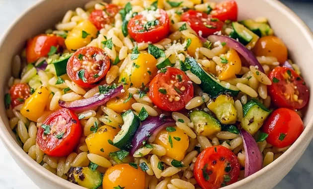 A bowl of colorful orzo pasta mixed with roasted zucchini, bell peppers, onions, and cherry tomatoes, garnished with fresh herbs and feta — the perfect Roast Vegetable Dinner and Healthy Vegetable Main Dish Recipes for a quick, vibrant weeknight meal.
