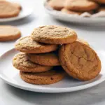 A stack of soft, gluten-free pumpkin cookies dusted with cinnamon on a rustic plate, styled for fall.