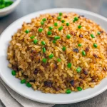 Baking dish of golden French onion butter rice with crisped edges, garnished with chopped parsley and a sprinkling of cheese — a savory side perfect for weeknight dinners and holiday spreads.