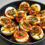 Close-up of halved deviled eggs topped with chili-garlic and herbs — a bold Spicy Egg Recipes idea and tasty Snack Ideas Spicy, plated with dipping Boiled Egg Sauce for more flavor and perfect for new Boiled Eggs Ideas.