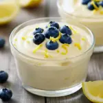 Glass jar of pale yellow Whipped Cottage Cheese Lemon Mousse topped with blueberries — a light Lemon Cottage Cheese Mousse that’s Desserts Low Calorie and fits into Lemon Recipes Dessert Healthy menus.