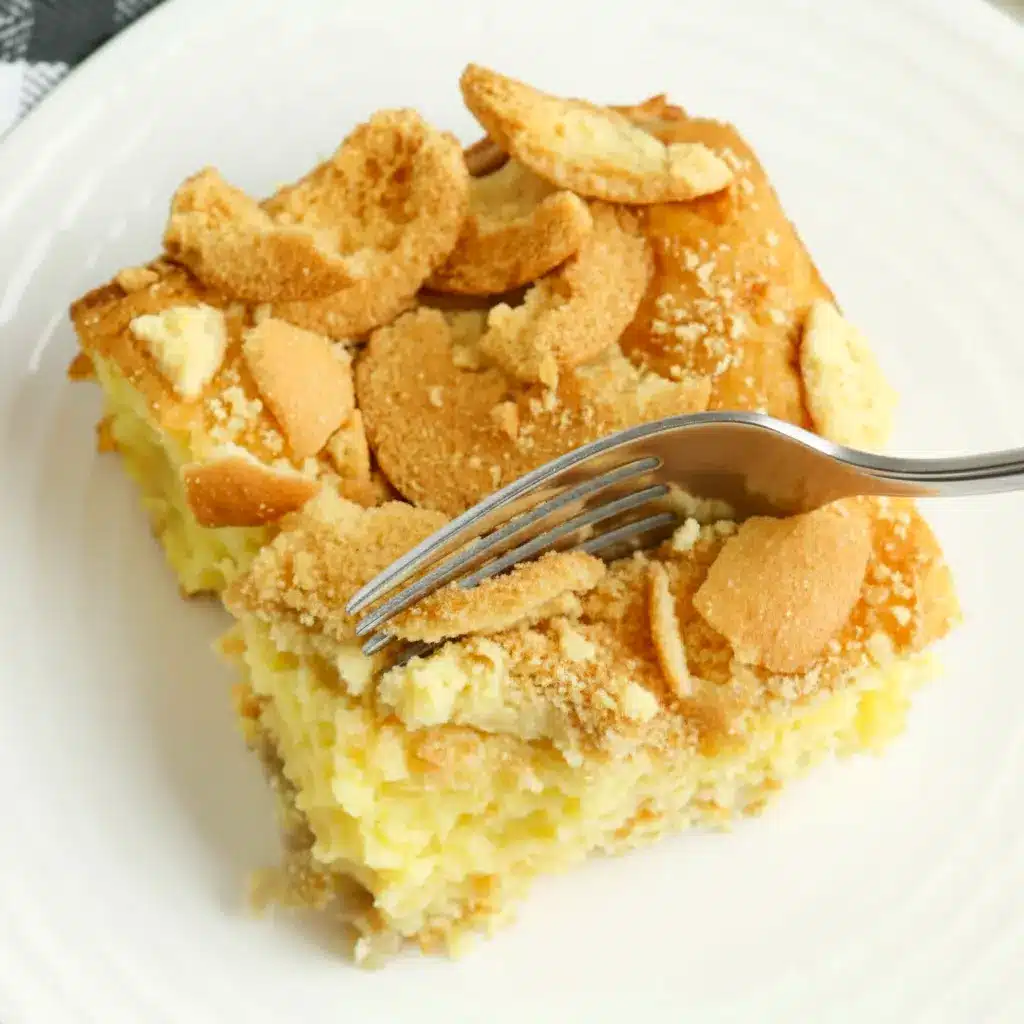 Golden banana blondie squares topped with sliced bananas and crushed vanilla wafers on a serving plate, Banana Pudding Brownie.