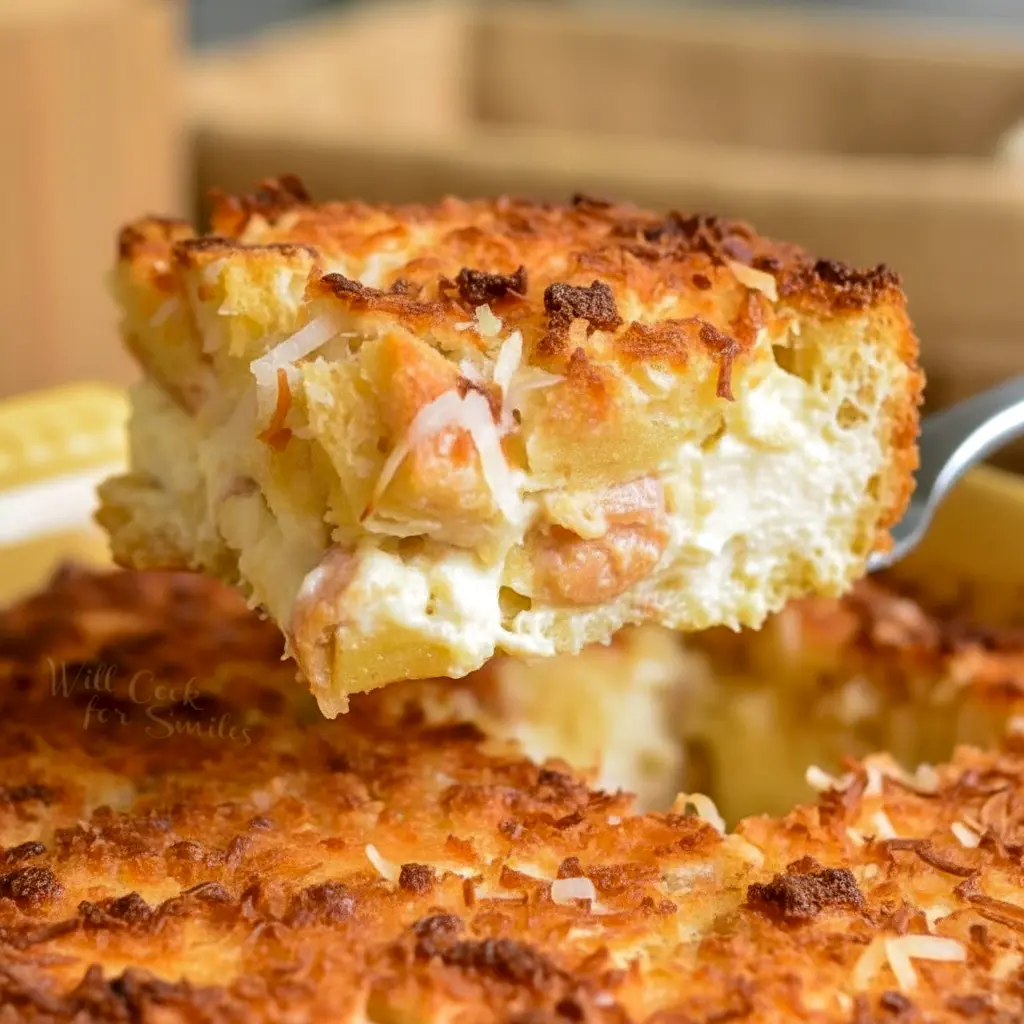 Warm slice of coconut cheesecake bread pudding topped with toasted coconut.
