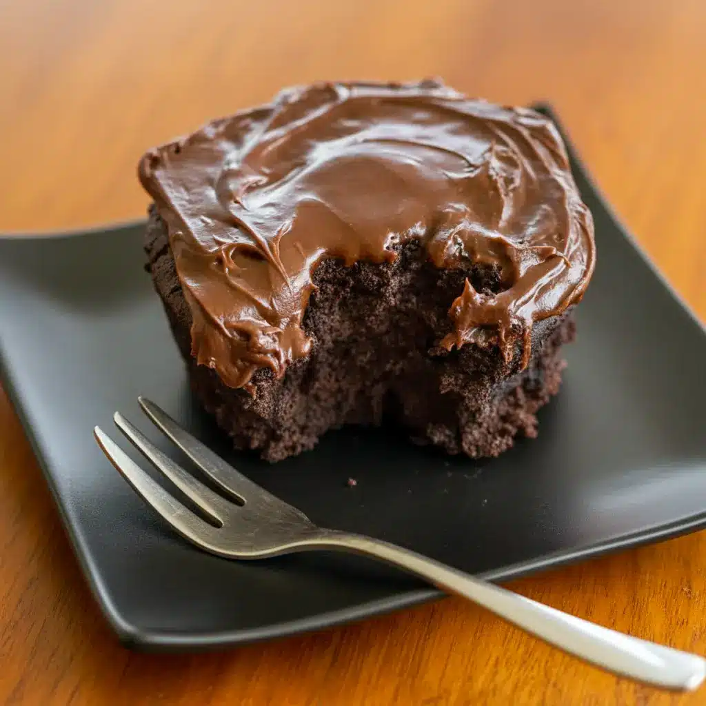 Fudgy chocolate mug cake in a white mug, spoon scooping a warm, gooey center (topped with a small dollop of whipped cream).