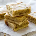 Golden-brown blondie squares dotted with tender apple pieces, drizzled with glossy maple glaze and dusted with cinnamon — a warm, fall dessert ready to serve, Fall Blondies Recipe.