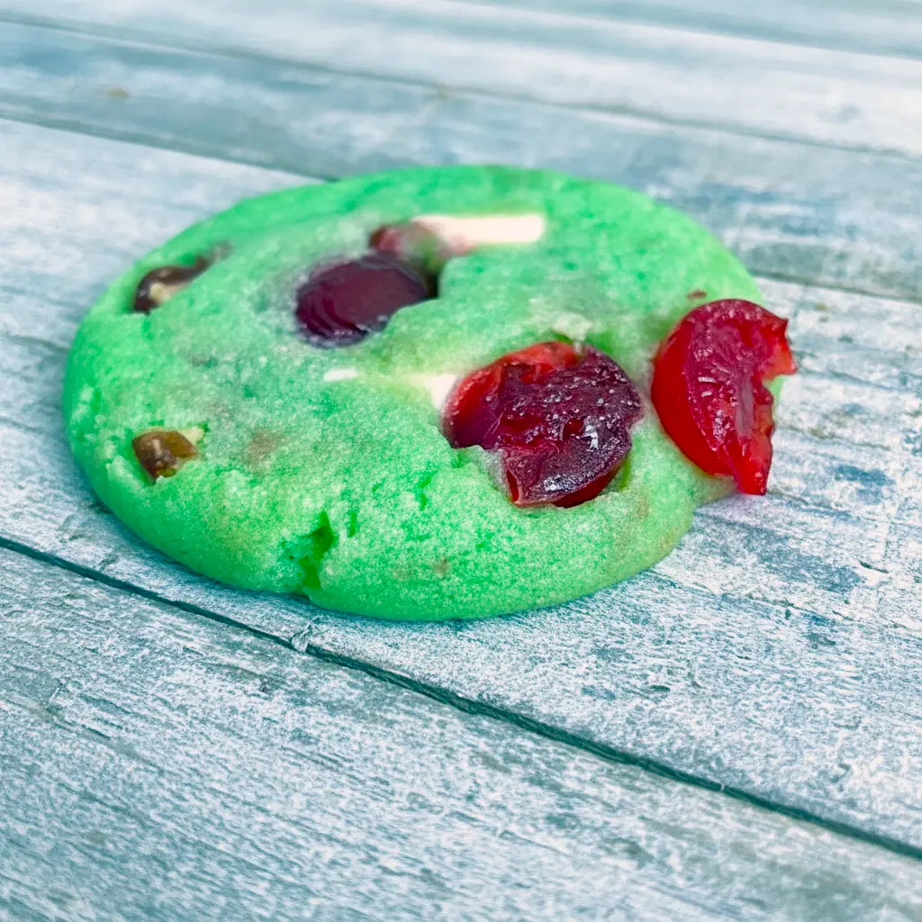 Close-up shot of green crinkle cookies filled with cherries and white chocolate chips, showcasing festive Pistachio And Cherry flavor with the cozy texture of Pistachio Cherry Meltaways, Pistachio Cherry Meltaway Cookies, and Pistachio Pudding Cherry Cookies, styled with the fruity look of Dried Cherry Pistachio Cookies, perfect for fans of Cherry Cookies Recipes, Pistachio Recipes, Cherry Cookies, and soft Pistachio Cookies.