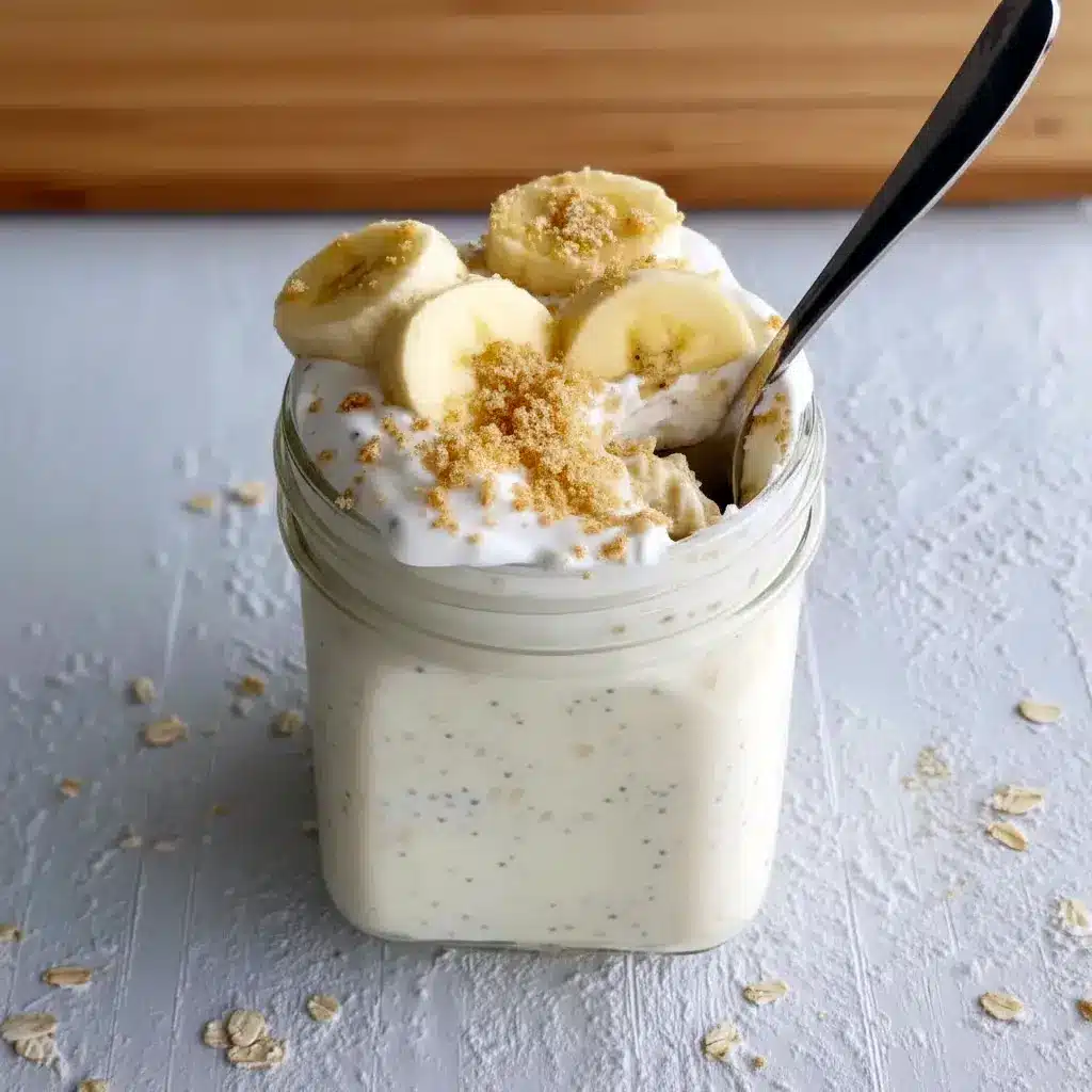 Close-up of a mason jar filled with layered Banana Cream Pie Overnight Oats, showing creamy yogurt and mashed banana with a graham cracker crumble — a dreamy Overnight Oatmeal With Yogurt that's an Overnight Oats Recipe Easy to prep and a serious candidate for the Best Overnight Oats Recipe; styled as one of my favorite Oat Recipes Healthy and an Overnight Oats Recipe Healthy grab-and-go Overnight Oatmeal, inspired by Banana Cream Pie and perfect for Breakfast Meal Prep.