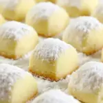Powdered sugar–dusted butter cookies on a festive plate, showing the tender, crumbly texture and golden edges — perfect holiday melt-in-your-mouth treats, Melt In Your Mouth Cookies.
