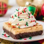 Close-up of chilled Eggnog Brownies topped with a dusting of nutmeg and a swirl of whipped cream.