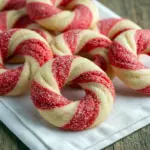 Close-up of round sugar cookies studded with crushed peppermint, arranged on a festive plate, Festive Christmas Cookies Recipes.