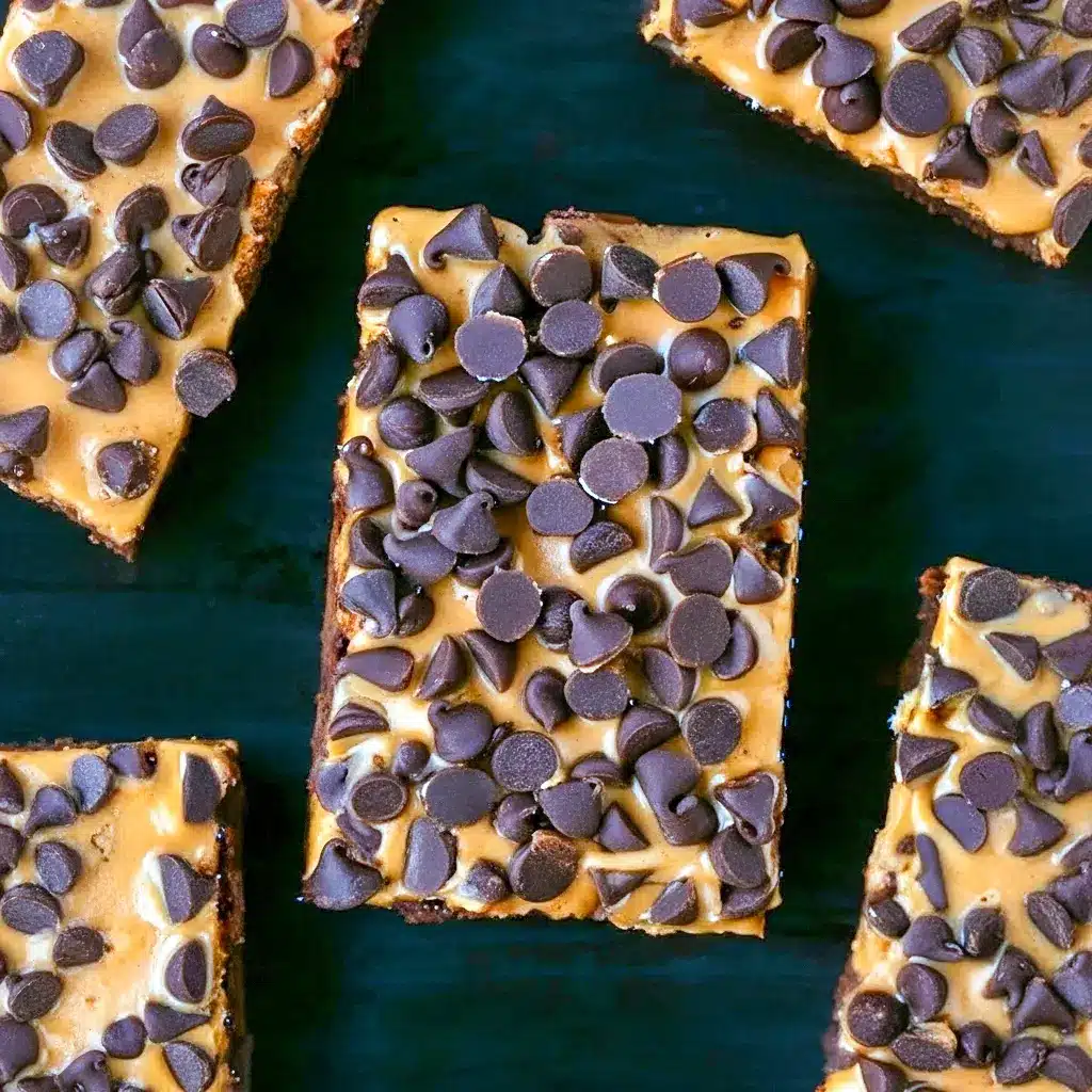 Stacked pumpkin-chocolate brownie bars on parchment, topped with a smear of peanut butter and sprinkled mini chocolate chips, Pumpkin Workout Brownies.