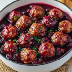 Glossy cranberry-glazed meatballs piled in a festive bowl, garnished with rosemary and served with toothpicks for easy snacking, Easy Cute Christmas Appetizers.