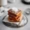 Stack of golden Best Gingerbread Waffles topped with whipped cream and syrup, styled for a cozy Christmas Breakfast Waffles spread.