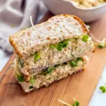 Open-faced chickpea salad sandwich on whole-grain bread topped with romaine, tomato slices, and chopped parsley, styled on a wooden board, Chickpea Sandwich Lunch Idea.