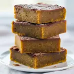 Snickerdoodle Blondies Recipe squares on a wooden board, cinnamon-sugar crust and pumpkin-hued interior visible, styled for a cozy Thanksgiving Desserts spread.