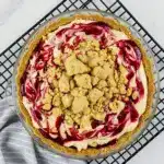 Slice of peanut butter and jelly pie with a crunchy cookie crust, swirled peanut butter filling, glossy raspberry jelly pockets and toasted crumb topping on a plate, Pie Dessert.
