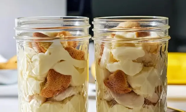 Creamy jar of Healthy And Easy Desserts protein banana pudding layered with crushed vanilla wafers and banana slices.