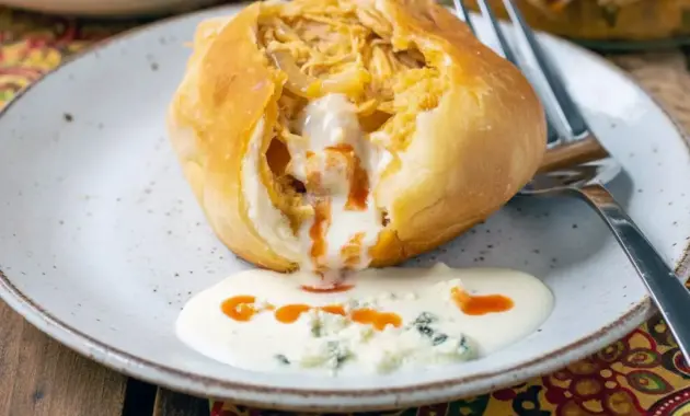 Easy Game Day Dinner Ideas: golden Buffalo Chicken Bombs on a platter, brushed with butter and served with blue cheese dressing and celery sticks.