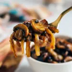 Golden sautéed mushrooms and onions in a skillet, glossy and ready to spoon over a grilled steak, Caramelized Onions And Mushrooms.