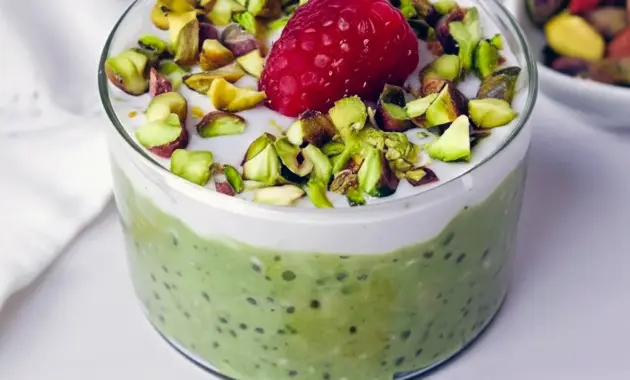 Jar of Raspberry Pistachio Overnight Oats layered with dairy-free yogurt, fresh raspberries, and chopped pistachios — a portable Overnight Oats Plant Based breakfast.