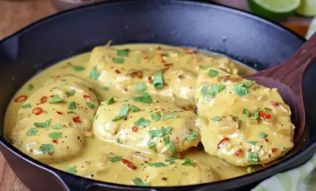 Skillet of Creamy Coconut Lime Chicken over jasmine rice, garnished with chopped cilantro and a lime wedge.