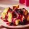 Close-up of a slice of Overnight Blueberry French Toast drizzled with glossy Blueberry Sauce, topped with fresh berries and a sprinkle of powdered sugar.