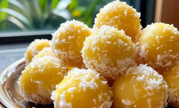 A platter of Pineapple Christmas Balls rolled in shredded coconut and arranged with festive greenery — a colorful Pineapple Recipes holiday treat ready to serve.