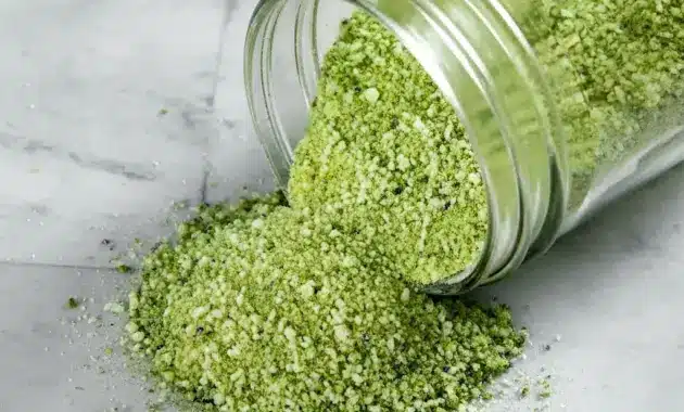 Jar of green-speckled Jalapeno Salt Recipe with fresh jalapeños and a lime wedge — a simple example of Infused Salt Recipes.