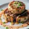 Close-up of golden tuna cakes topped with creamy sriracha-lime mayo and sliced scallions — a tasty example of Spicy Tuna Recipe Ideas and a crunchy Canned Tuna Appetizer.