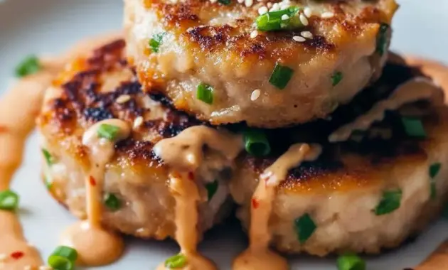 Close-up of golden tuna cakes topped with creamy sriracha-lime mayo and sliced scallions — a tasty example of Spicy Tuna Recipe Ideas and a crunchy Canned Tuna Appetizer.