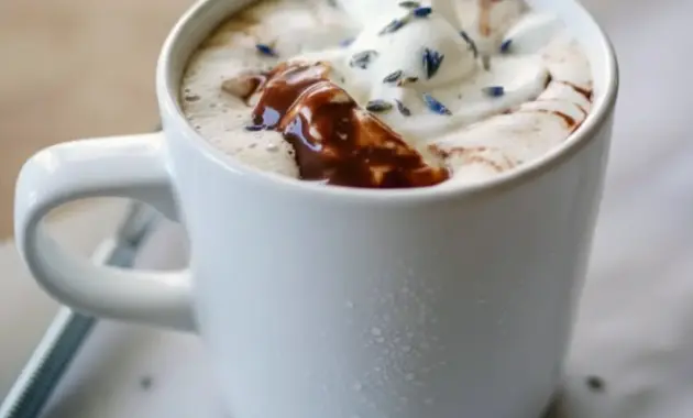 Lavender Hot Chocolate — frothy mug of lavender-infused hot chocolate topped with whipped cream and a few lavender buds, styled on a rustic wooden tray.