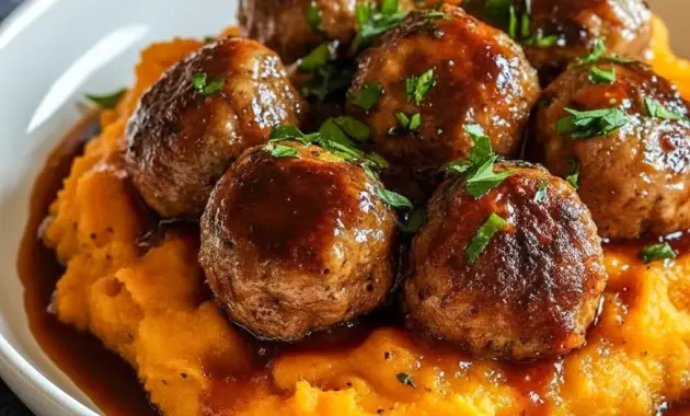 Pork Meatballs stacked on sweet potato mash, drizzled with bourbon-maple sauce and sprinkled parsley — a cozy Pork Meatball Dinner shot (close-up).