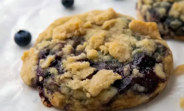 Thick Blueberry Muffin Cookies with golden streusel, jam pockets, and plump blueberries on parchment — close-up of a chewy, bakery-style cookie.