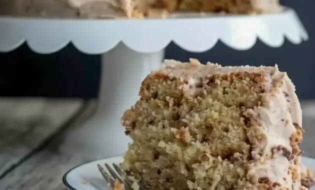 Banana Toffee Cake — slice showing banana-speckled crumb, glossy browned-butter toffee buttercream, and scattered toffee bits on top.