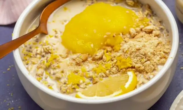 Lemon Cheesecake Overnight Oats in a jar, creamy and pale yellow, topped with lemon zest and fresh berries — a ready-to-eat Creamy Lemon Overnight Oats breakfast.