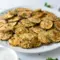 A plate of Crispy Baked Zucchini Chips with a crunchy golden coating, served as Healthy Baked Zucchini Snack with dipping sauce on the side.