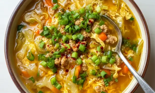 Steaming bowl of Egg Roll Soup with ground pork, shredded cabbage, carrots, and sliced green onions, ready to serve.
