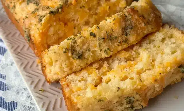 Loaf of Cheddar Bay Biscuit Bread sliced on a wooden board, topped with garlic-butter glaze and parsley — a delicious Side Bread Recipes option to pair with bowls of soup.