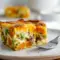 Slice of golden Sweet Potato Egg Casserole showing sweet potato cubes, melted cheese, and sausage, garnished with herbs — a hearty Breakfast Potato Bake perfect for meal prep.