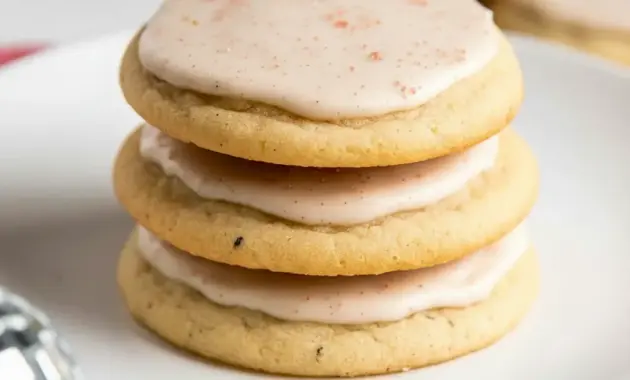 A stack of iced Taylor Swift Chai Cookies on a plate with a warm mug of tea, styled as a cozy homemade dessert.