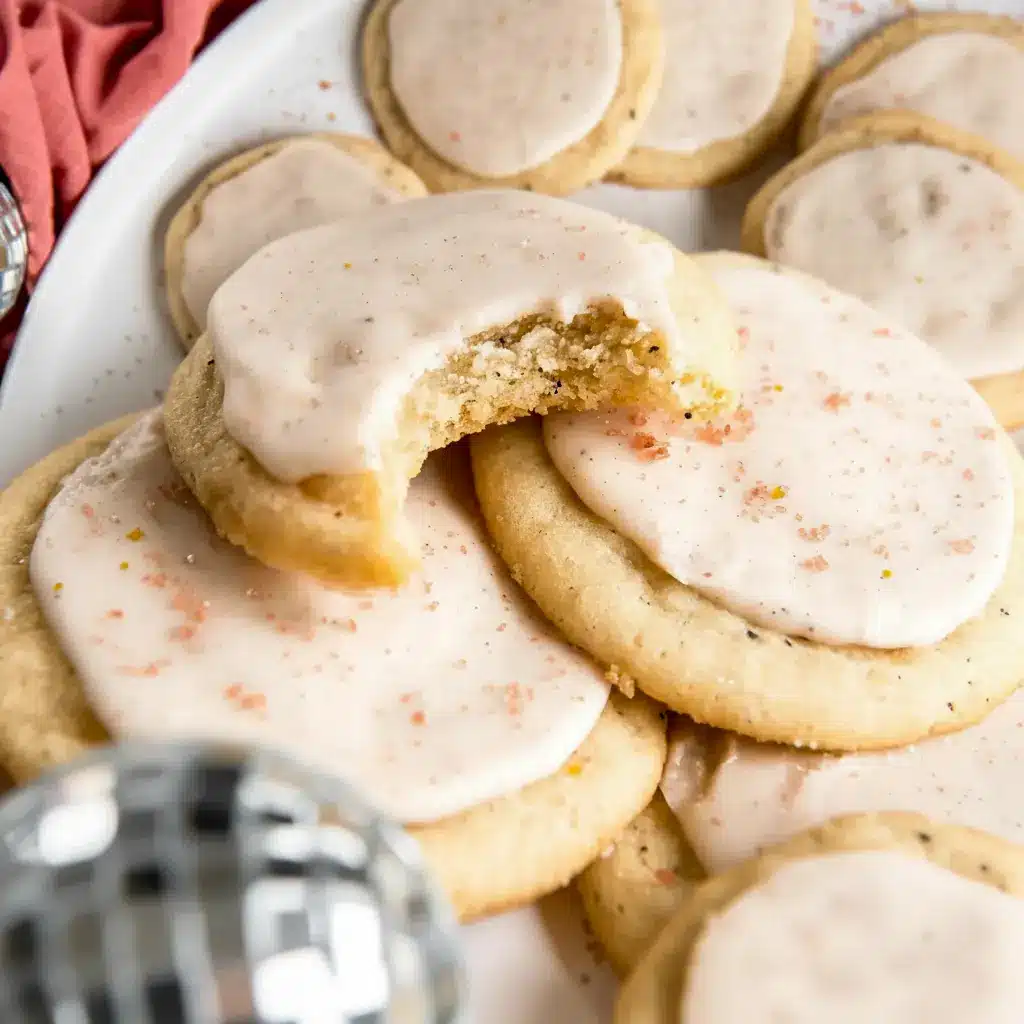A stack of iced Taylor Swift Chai Cookies on a plate with a warm mug of tea, styled as a cozy homemade dessert.