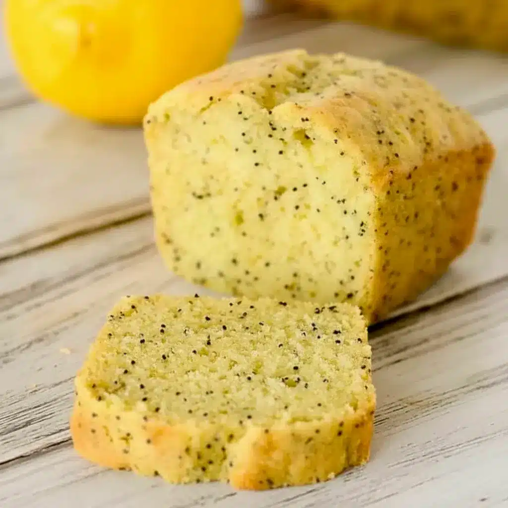 A sliced loaf of Lemon Poppy Seed Zucchini Bread with a soft golden crumb and visible poppy seeds, styled as a fresh Lemon Poppy Seed Dessert for Spring Baking Ideas.