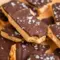 Greek Yogurt Bark on parchment, broken into rustic pieces with peanut-butter swirls, a dark chocolate topping, and a sprinkle of flaky sea salt — a portable Peanut Butter Chocolate Snack.