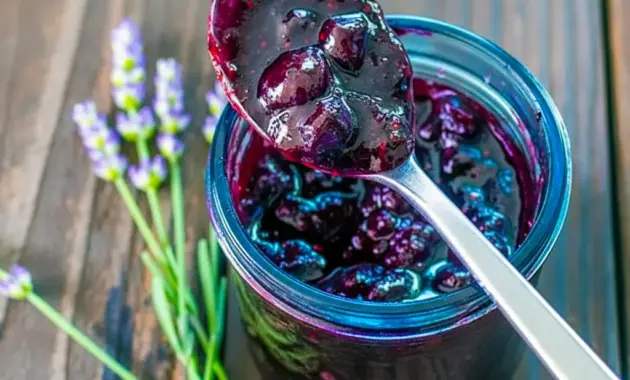 A jar of Blueberry & Lavender Jam with a spoon beside it, styled as a beautiful Homemade Lavender Jam Recipe for toast and gifting.