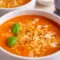 A bowl of High Protein Tomato Soup topped with basil and parmesan, styled as a comforting Creamy Healthy Soup.