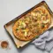 Apple Bacon Pizza with Caramelized Onions — Fall Pizza Toppings Done Right Sliced pizza on a wooden board topped with thin apple slices, crumbled bacon, caramelized onions and melted fontina and cheddar cheese.