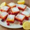 Baking with Fresh Cranberries Try These Irresistible Cranberry Lemon Bars!1 Close-up of golden Christmas Lemon Bars with layers of tart cranberry and lemon custard dusted with powdered sugar – the ultimate Baking With Fresh Cranberries dessert for the holidays.