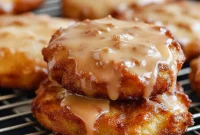 Golden Baked Fritters Recipe piled on a plate, each glazed and studded with apple chunks — the ultimate Best Apple Fritters Recipe that doubles as Breakfast Stuff or cozy Old People Desserts. A tray of Homemade Pastries Easy enough for weeknights, inspired by Seasonal Baking Recipes and adaptable with Canned Apple Recipes Desserts, delivering Soft Apple Recipes comfort as the ultimate Warm Food Recipes.