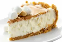 Slice of no-bake fluffernutter pie with marshmallow filling, peanut butter drizzle and crunchy graham cracker crust on a plate.